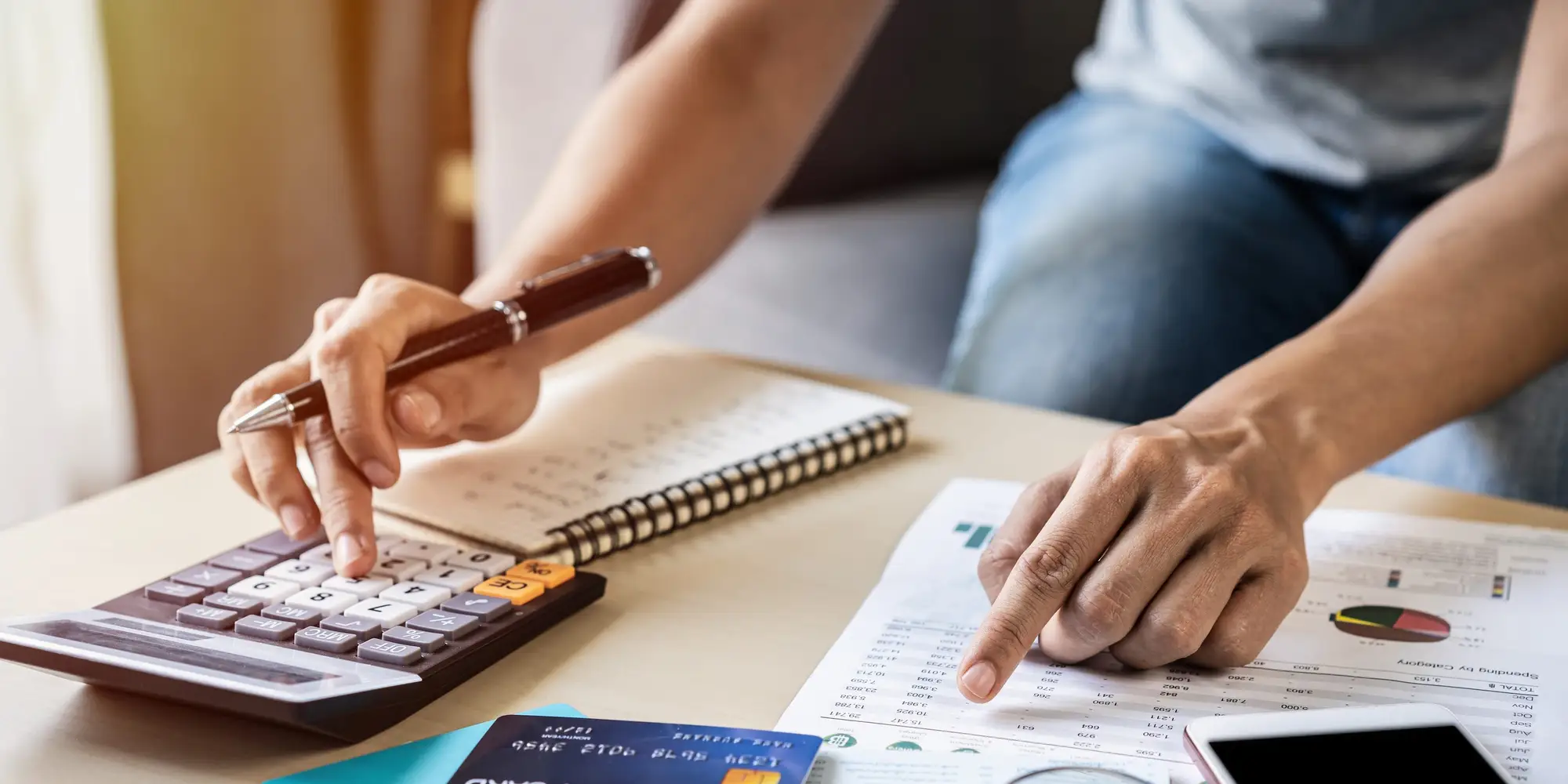 A person using a calculator and pen while reviewing financial documents.