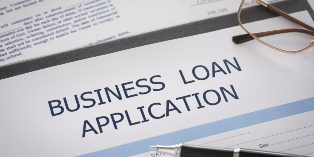 Business loan application form with pen and eyeglasses placed on the document, ready to be filled and submitted.